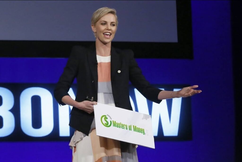 Charlize Theron Holding a Masters of Money LLC Logo Sign Photo